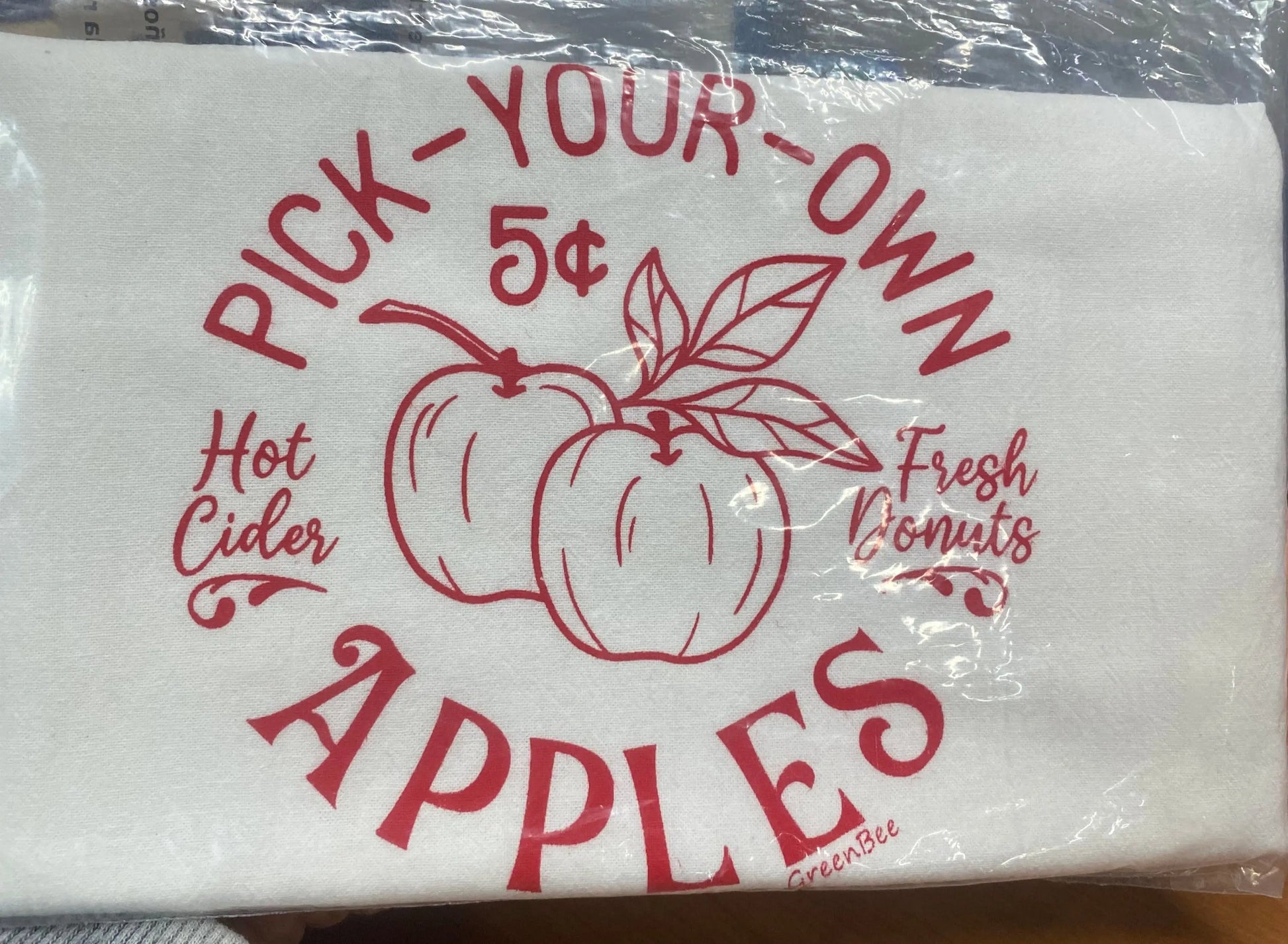 A white cotton kitchen towel with red text and illustrations, featuring the phrase 'Pick-Your-Own Apples' along with images of apples and the price '5 cents'.
